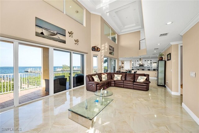 living room featuring a water view, ornamental molding, and a high ceiling