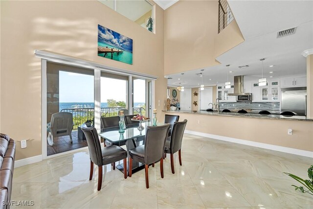 dining space with a water view and a high ceiling