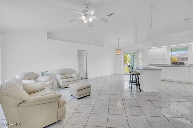 living room featuring sink, vaulted ceiling, light tile patterned floors, and ceiling fan with notable chandelier