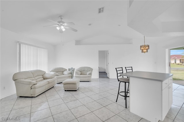 living room with lofted ceiling, light tile patterned floors, and ceiling fan with notable chandelier