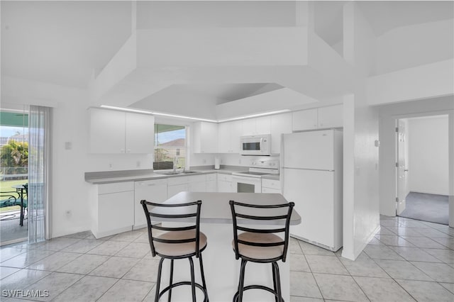 kitchen with white cabinets, a wealth of natural light, and white appliances