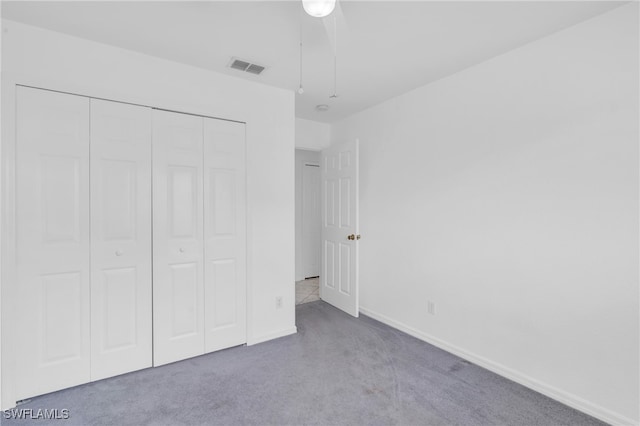 unfurnished bedroom featuring a closet, light colored carpet, and ceiling fan