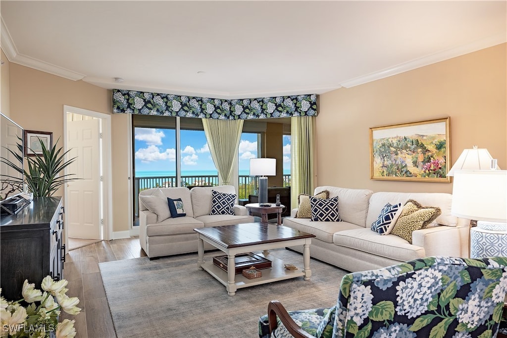 living room with a water view, ornamental molding, and light wood-type flooring