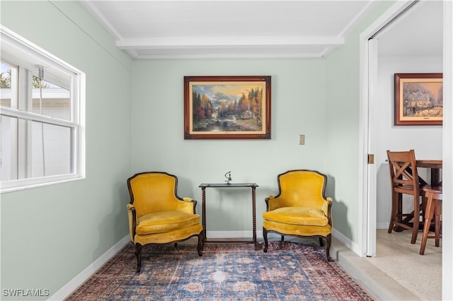 sitting room with dark colored carpet and beam ceiling