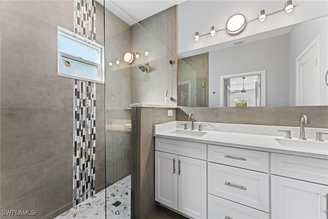 bathroom with a tile shower and vanity