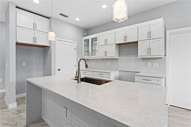 kitchen featuring sink, pendant lighting, and white cabinets