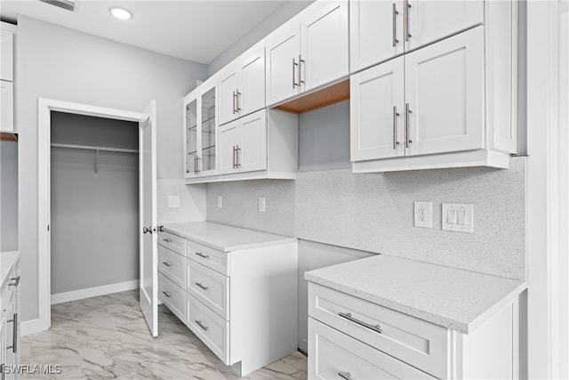 kitchen featuring decorative backsplash, white cabinets, and light stone counters