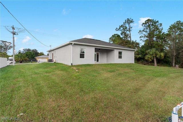 back of property with central air condition unit and a lawn