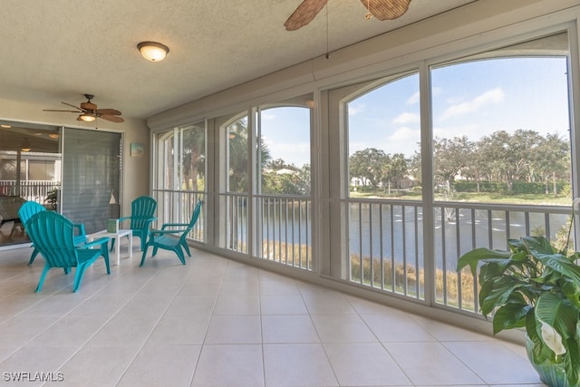 sunroom with a water view and ceiling fan