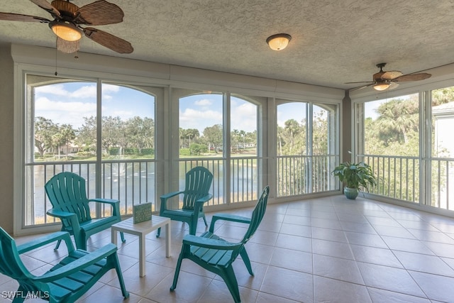 sunroom with a wealth of natural light, a water view, and ceiling fan