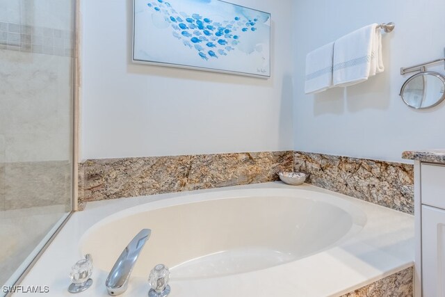 bathroom with vanity and tiled tub