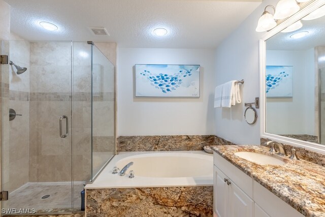 bathroom featuring vanity, a textured ceiling, and separate shower and tub