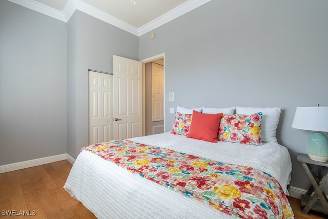 bedroom featuring ornamental molding, wood-type flooring, and a closet