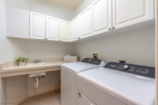 washroom featuring washing machine and dryer, cabinets, sink, and tile patterned floors