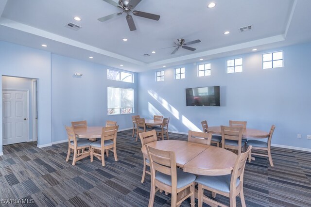 carpeted dining room featuring ceiling fan and a raised ceiling