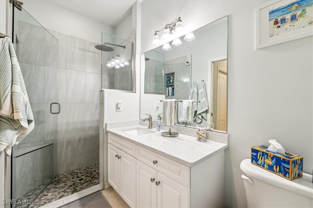 bathroom with toilet, tile patterned flooring, vanity, and a shower with door