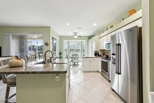 kitchen with sink, appliances with stainless steel finishes, a kitchen bar, and white cabinetry