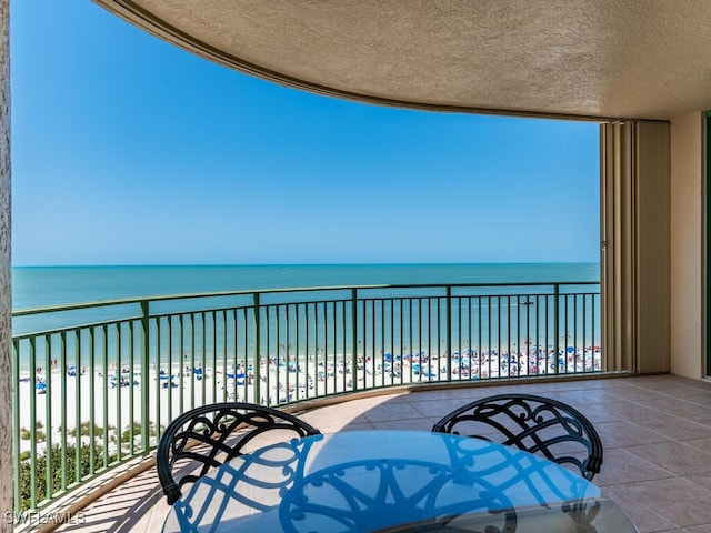 balcony with a water view and a view of the beach