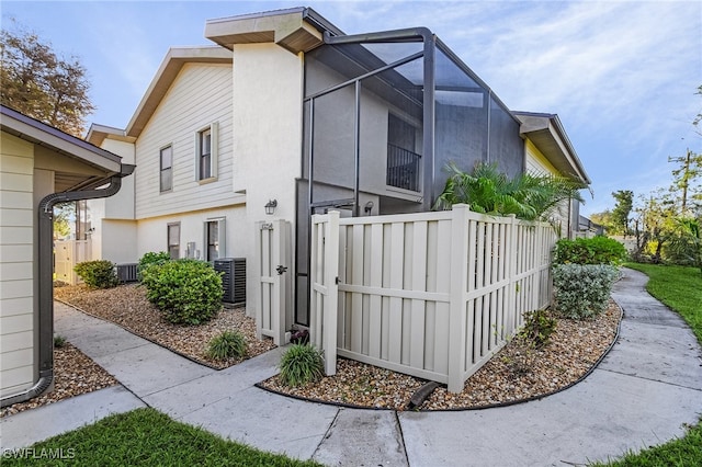 view of home's exterior featuring central AC unit and glass enclosure