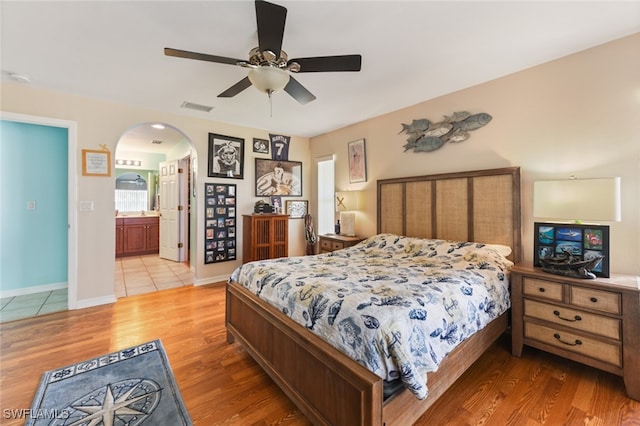 bedroom with light hardwood / wood-style flooring, ceiling fan, and ensuite bathroom