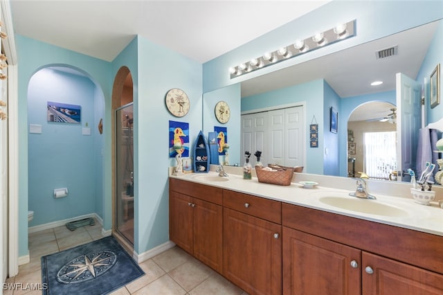 bathroom with tile patterned floors, toilet, a shower with door, vanity, and ceiling fan