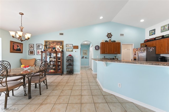 kitchen featuring lofted ceiling, an inviting chandelier, light tile patterned floors, decorative light fixtures, and stainless steel fridge