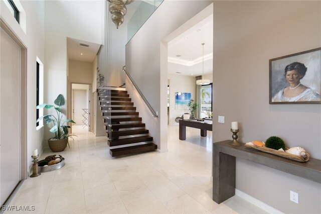 tiled entryway featuring a towering ceiling and a tray ceiling