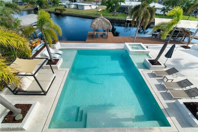 view of swimming pool featuring an in ground hot tub, a water view, and a patio area