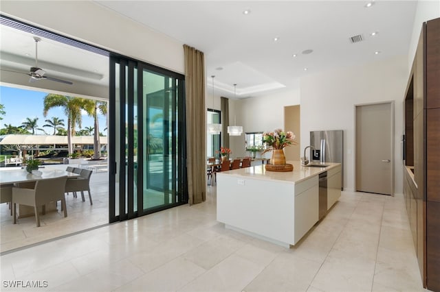 kitchen with a kitchen island with sink, white cabinets, sink, ceiling fan, and stainless steel appliances