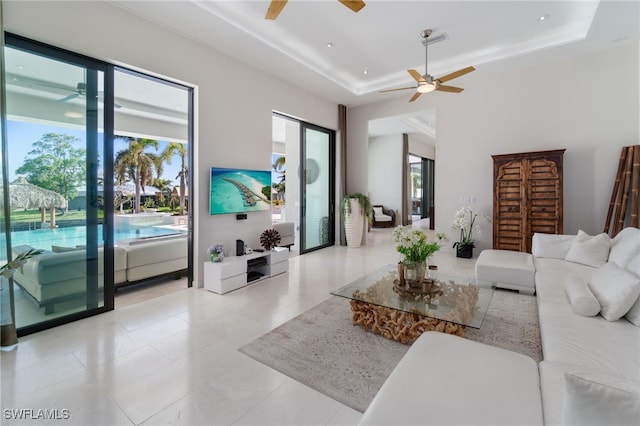 living room with ceiling fan and a raised ceiling