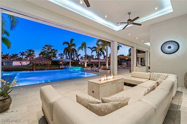 pool at dusk with ceiling fan and pool water feature