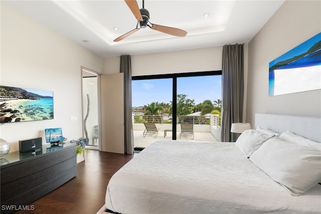 bedroom with a raised ceiling, ceiling fan, dark hardwood / wood-style flooring, and access to exterior