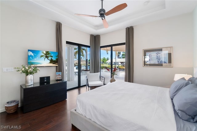 bedroom featuring access to outside, a raised ceiling, ceiling fan, and dark hardwood / wood-style flooring