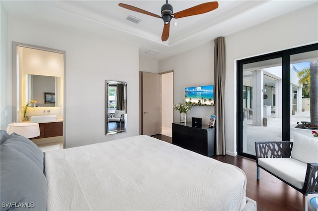 bedroom with dark wood-type flooring, access to outside, a raised ceiling, ceiling fan, and connected bathroom