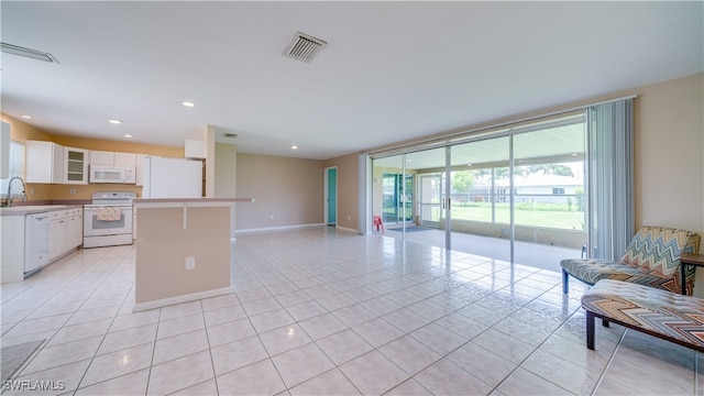 kitchen featuring white cabinets, light tile patterned floors, white appliances, and sink