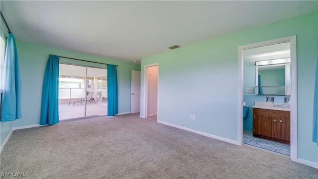 unfurnished bedroom featuring light carpet, access to outside, ensuite bath, and sink