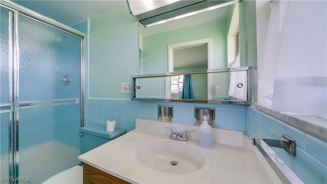 bathroom with vanity, toilet, a shower with door, and tile walls