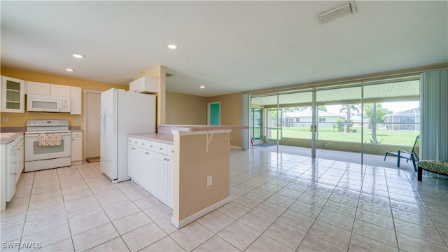 kitchen featuring a breakfast bar area, white cabinets, light tile patterned flooring, and white appliances