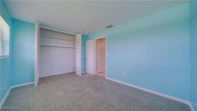 unfurnished bedroom featuring light carpet and a closet