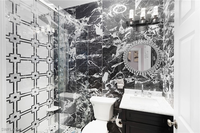 bathroom with tile walls, vanity, toilet, and an enclosed shower