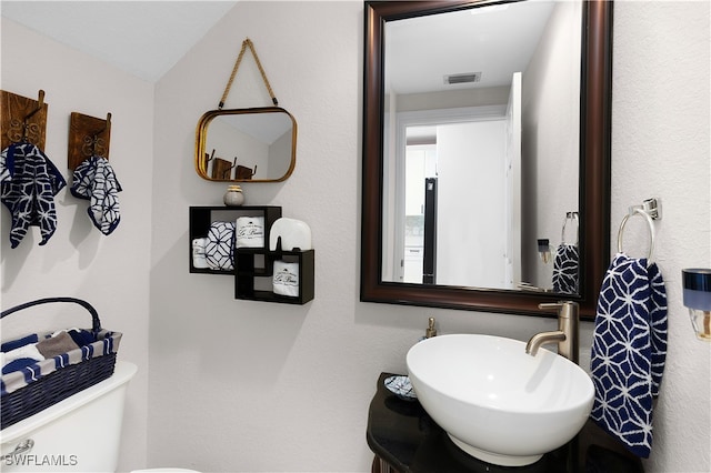 bathroom with vanity, toilet, and lofted ceiling