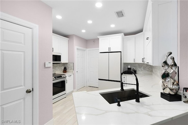 9801 Boraso Way Unit 103, Fort Myers, FL 33908 - kitchen featuring white appliances, white cabinetry, decorative backsplash, light stone counters, and recessed lighting