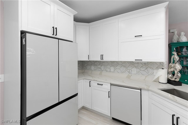 kitchen featuring light stone counters, white cabinetry, white fridge, and tasteful backsplash