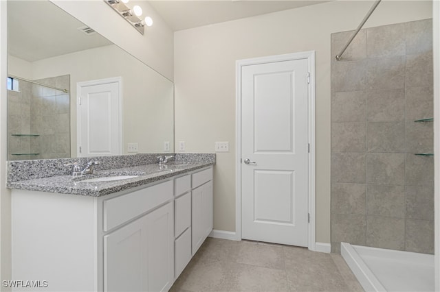 bathroom with vanity, a tile shower, and tile patterned floors