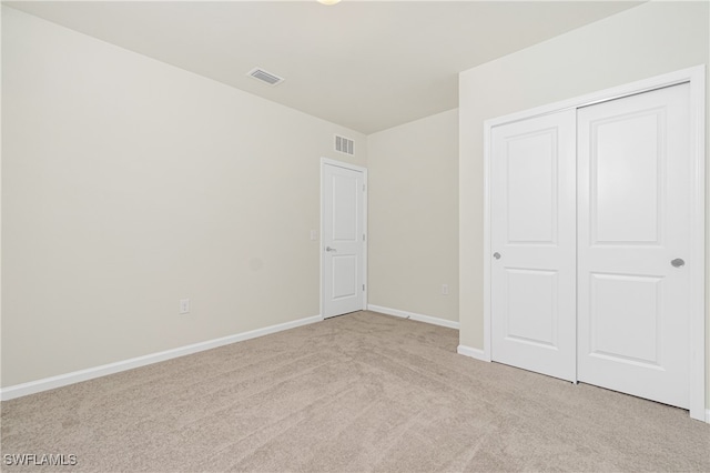 unfurnished bedroom featuring light colored carpet and a closet