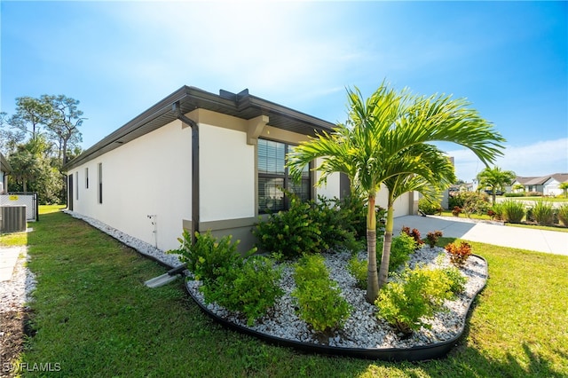 view of side of property with a yard and central air condition unit