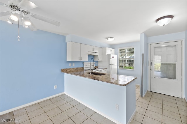 kitchen with sink, kitchen peninsula, white cabinetry, dark stone countertops, and white refrigerator