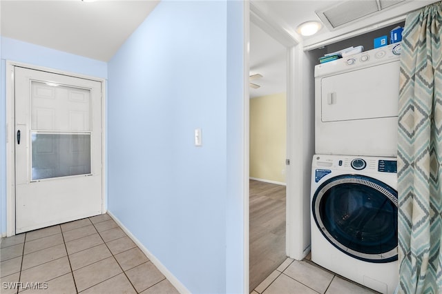 washroom with stacked washer / dryer and light tile patterned floors