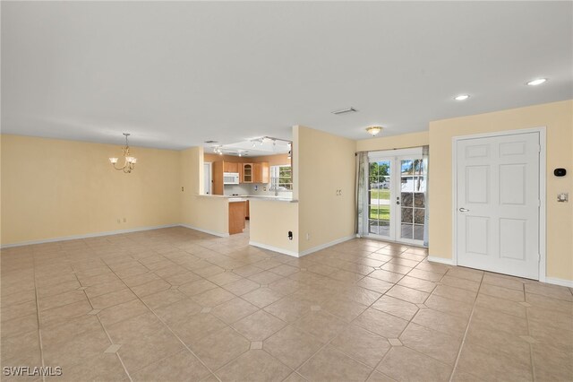 unfurnished living room with a notable chandelier, french doors, and light tile patterned flooring