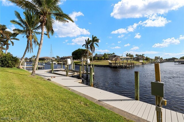 view of dock with a water view and a lawn